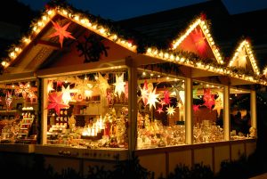 Ein beleuchteter Weihnachtsmarkt-Stand in der Dunkelheit. Viele Lichter, Laternen, Weihnachtsdeko. Stimmungsvoll.